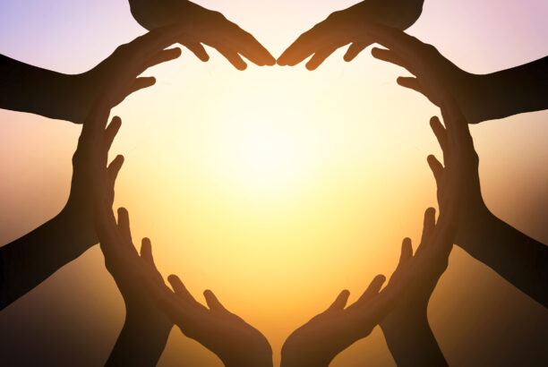 Hands making a heart shape with the sun in the background